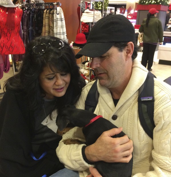 Two People Hugging A Black And Tan Dachshund Mix