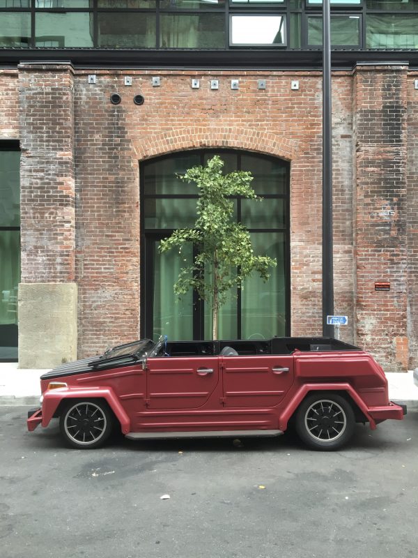 Volkswagen Thing Framed With Brick Building And Tree Behind