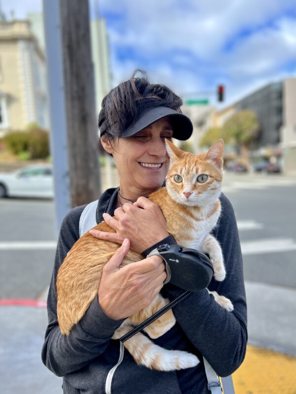 Woman Holding Marmalade Tiger Tabby Cat On City Street