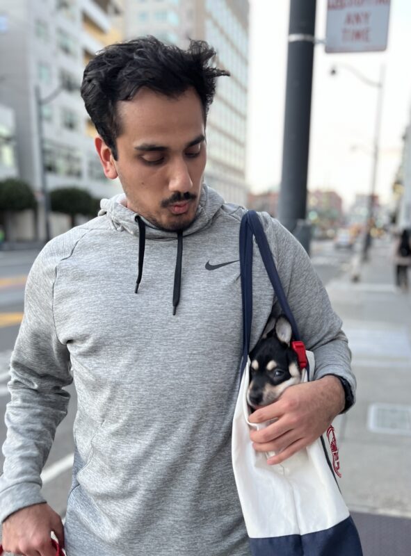 Man With Australian Kelpie Puppy In His Shoulder Bag