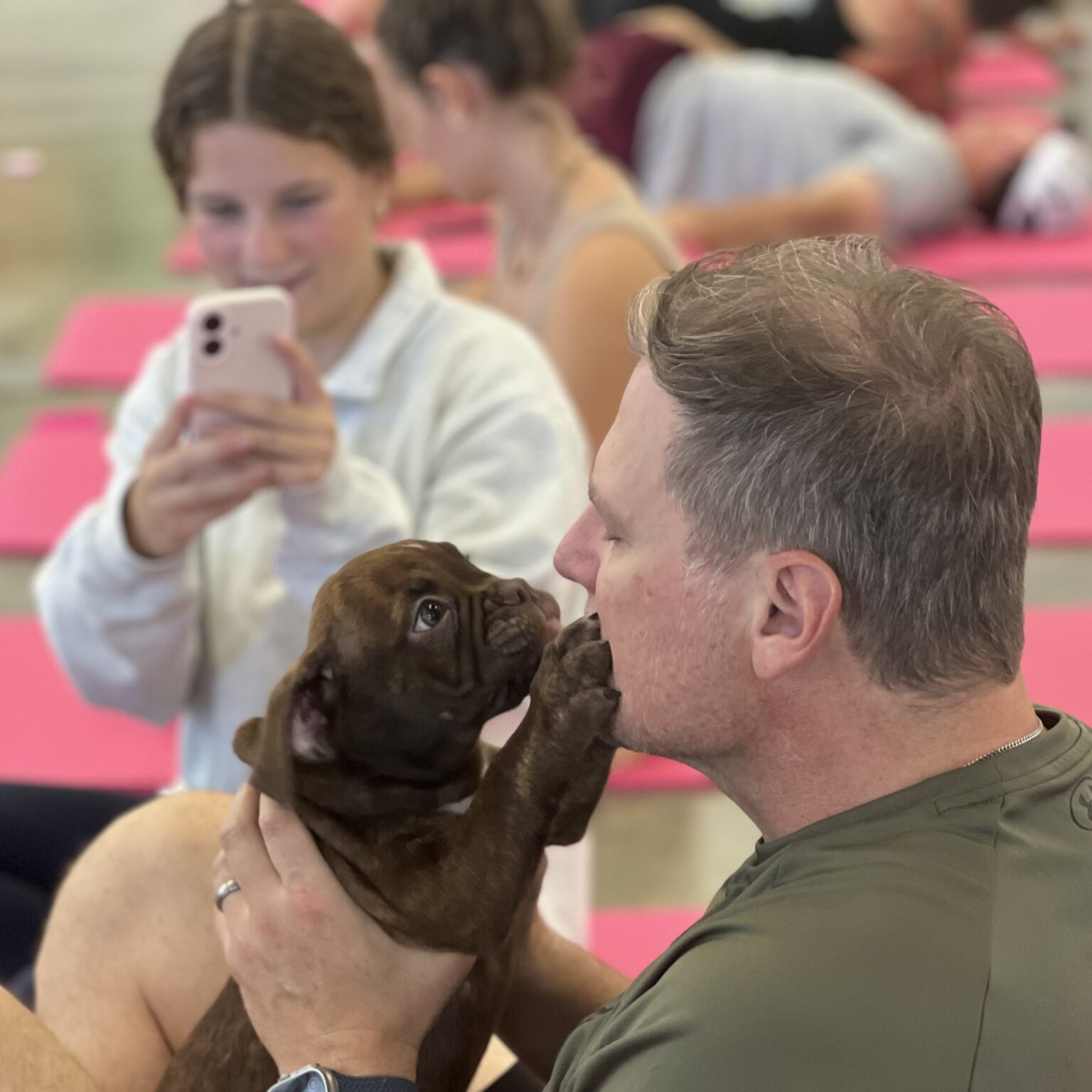 Man Holding Brown English Bulldog Puppy Near His Face